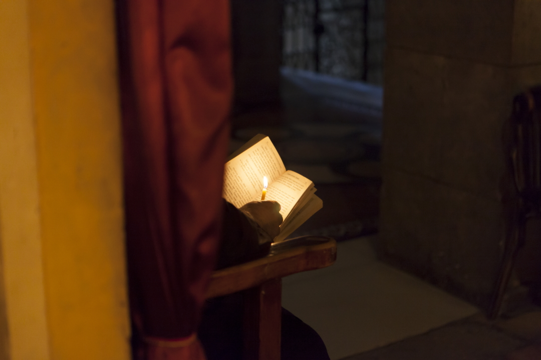 Reading the Bible with a cangle in a dark church